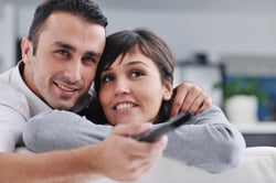 Relaxed young  couple watching tv at home in bright living room